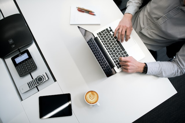 overhead of a pleasanton property management professional working on their laptop at a desk with a coffee cup